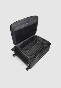 Maleta negra con carcasa rígida y interior espacioso. Cuenta con múltiples compartimentos, correas y ruedas suaves para facilitar la movilidad.