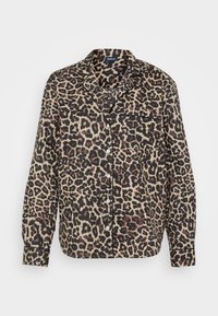 Leopardmønster skjorte i beige og svart stoff. Har krage, knappelukking foran, brystlomme og lange ermer med knappede mansjetter.