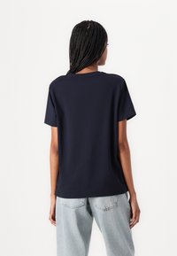 Mørkeblå kortermet T-skjorte med rund hals og en avslappet passform, kombinert med lyseblå denimjeans. Enkelt design, myk tekstur.