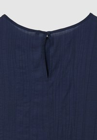 Top blu navy con un motivo testurizzato a coste; presenta un'apertura a chiave sul retro, chiusa con un piccolo bottone.