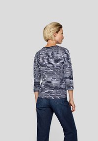 Langärmliges Oberteil in Marineblau und Weiß mit Rundhalsausschnitt, lockerer Passform und weichem Stoff, kombiniert mit dunkelblauen Jeans.