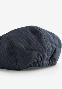 Dunkelblaues, strukturiertes Barett mit einem gesteppten Muster und gerafftem Bund. Hergestellt aus weichem Stoff, mit sichtbaren Nähten und runder Form.