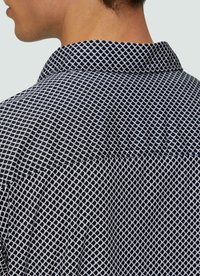 Navyblauwe shirt met een geometrisch wit rasterpatroon, een kraag en zichtbare stitching langs de achternaad.