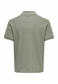 Polo à manches courtes vert olive avec un col classique et une bordure blanche subtile sur le col et les bords des manches, vu de dos.