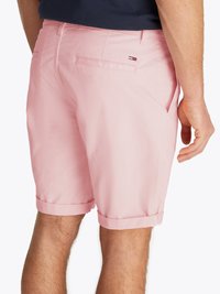 Calções de algodão cor-de-rosa com uma bainha dobrada, apresentando dois bolsos traseiros e uma pequena etiqueta com o logótipo da marca no bolso direito.