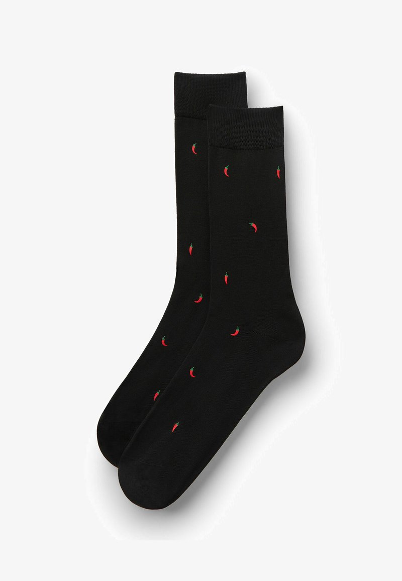 Chaussettes noires montantes avec des motifs de petits piments rouges répartis uniformément sur le tissu.