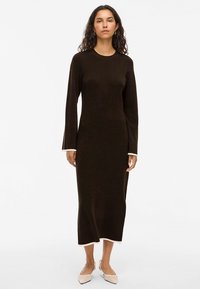 Robe marron à manches longues avec une coupe droite, dotée d'un col rond et d'une bordure blanche contrastante aux poignets et à l'ourlet; fabriquée en tissu doux.