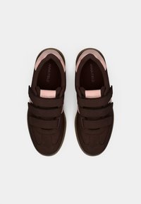 Baskets en velcro marron avec des accents roses, dessus en tissu texturé, bout rond et semelle en caoutchouc contrastante, avec un détail de double couture.