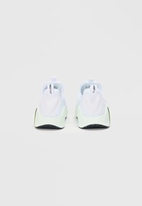 Hvite sneakers med en myk, teksturert overdel, som har en pull-tab, kontrasterende myntgrønne detaljer på sålen, og et gummimønster.