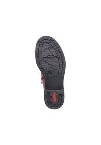 Semelle en cuir marron avec caoutchouc noir texturé. Présente un motif de semelle pour une meilleure adhérence et un logo de marque rouge intégré dans le talon.