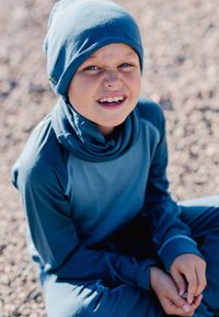 Blue, long-sleeve shirt and matching beanie made of soft fabric. The shirt has a high collar, while the beanie is snug-fitting.