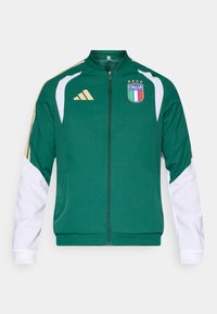 Zelená športová bunda s bielymi rukávmi, so zipsom a logom talianskej vlajky. Obsahuje zlaté akcenty a logo Adidas na hrudníku.