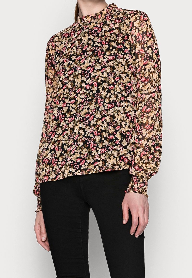 Blusa nera floreale con maniche lunghe e puff. Presenta piccoli fiori rosa e gialli, un collo alto e polsini arricciati. Realizzata in tessuto leggero.