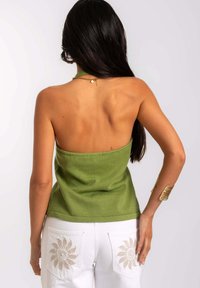 Groene gebreide tanktop met een aansluitend ontwerp, gecombineerd met witte broek met geborduurde zonpatronen op de zakken. Zachte textuur.