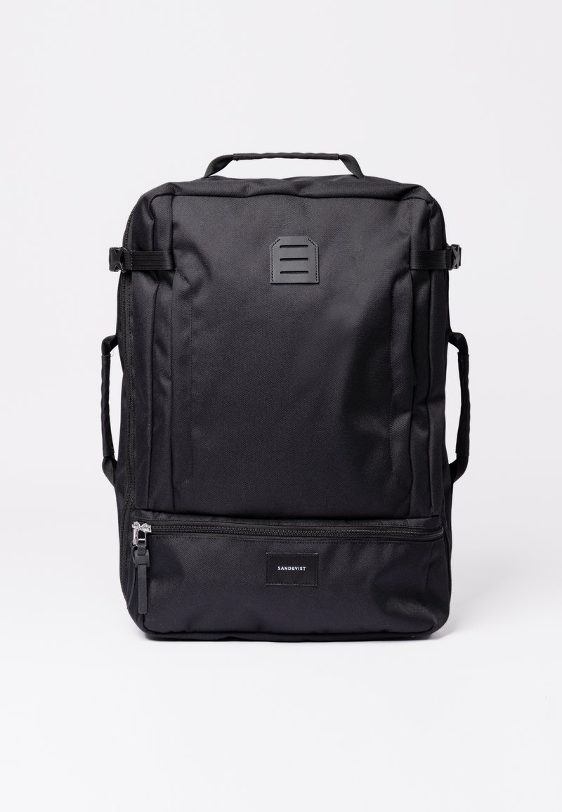 Black backpack made of durable fabric, featuring a top handle, adjustable straps, and a front zip pocket with a logo tag.