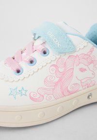 Hvite lær sneakers med rosa enhjørning broderi, blå detaljer, rosa snøring og borrelåsstropp. Rund gummisåle med dekorative detaljer.