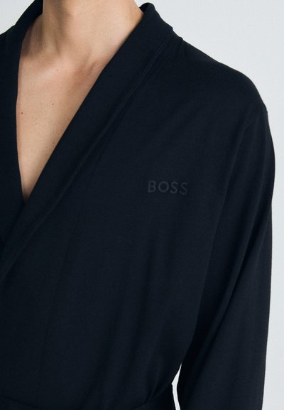 Robe noire en tissu doux, avec un col châle et une taille ceinturée. Logo BOSS discret embossé sur la poitrine. Manches longues.