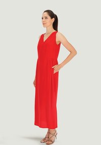 Czerwona, bezramienna sukienka maxi z dekoltem w serek, charakteryzująca się luźnym krojem i bocznymi kieszeniami. Gładki materiał elegancko opada do kostek.