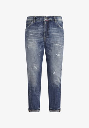 Verweerde spijkerbroek met een verloop van licht naar donkerblauw, met vervaagde plekken, opgerolde broekspijpen en een knoopsluiting.