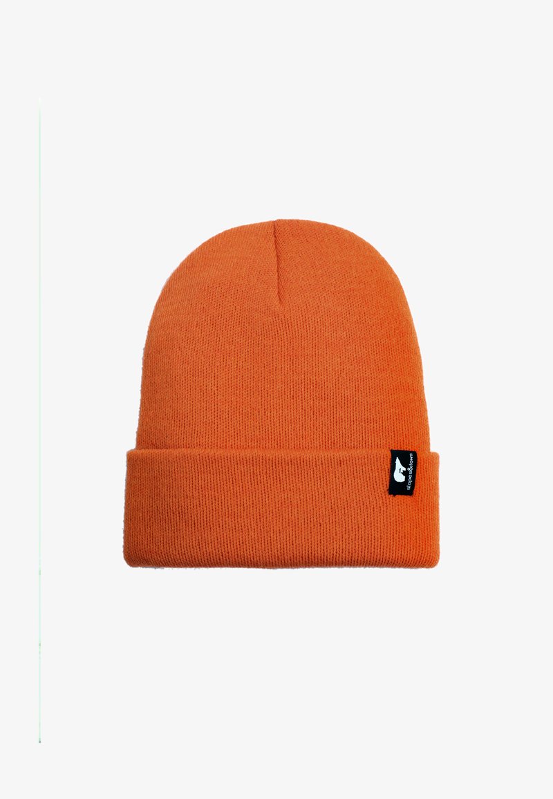 Bonnet en tricot orange avec un revers replié, fabriqué dans un tissu doux. Présente une petite étiquette noire avec du texte blanc sur le côté.