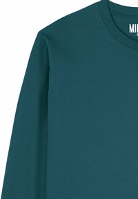 Chemise à manches longues et col rond en teal foncé, fabriquée dans un tissu en mélange de coton lisse avec des détails de couture minimalistes au niveau du col.