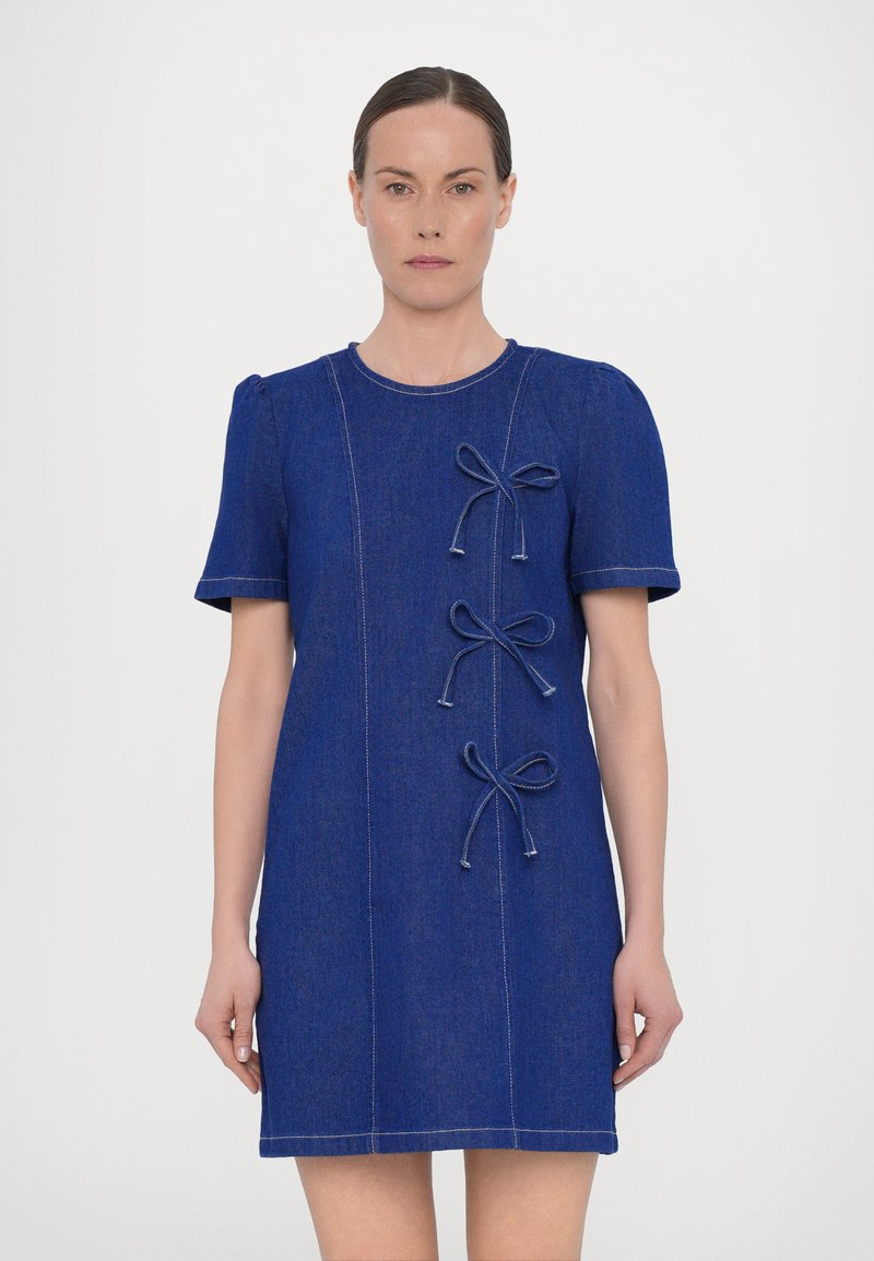 Blue denim dress with short sleeves, featuring three decorative bows and contrasting stitching. Simple, straight silhouette. No patterns.