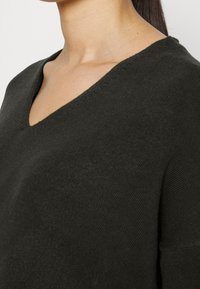 Ciemnoszary sweter dziany z dekoltem w kształcie V i krótkimi rękawami, oferujący teksturowaną powierzchnię i gładkie wykończenie.