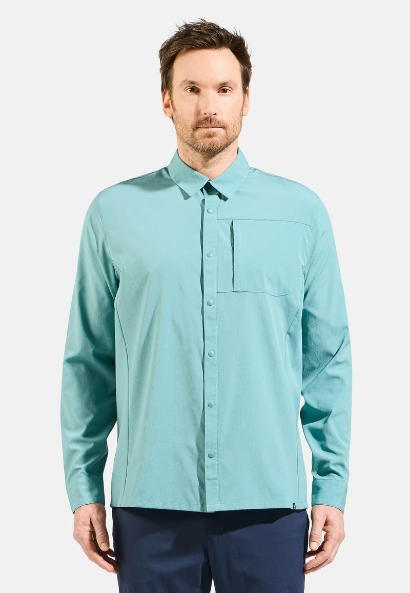 Light blue long-sleeve shirt with a button-down collar, front pocket, and textured fabric. Features a straight hem and subtle stitching.