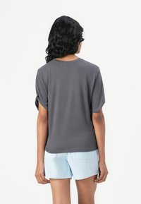 T-shirt gris à manches courtes avec un col arrondi et des ourlets roulés, associé à un short rayé bleu et blanc. Tissu en coton lisse.