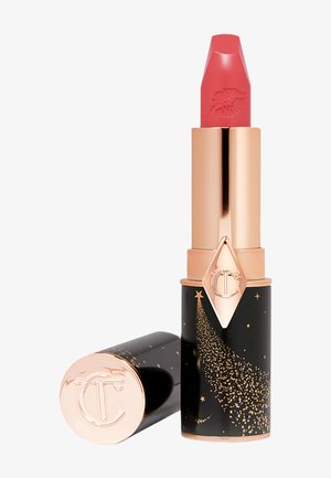 Rossetto rosa con punta appuntita, contenuto in un tubo nero decorato con stelle dorate e un logo in evidenza. Il tappo è di un metallico oro rosa.