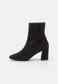 Stivaletto in camoscio blu scuro con punta affusolata e tacco spesso. Texture liscia, design minimal e cerniera laterale per una facile calzata.