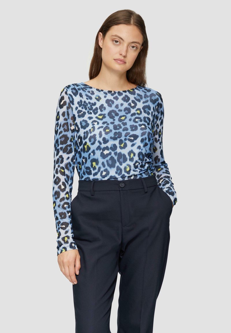 Lange mouwen, blauw luipaardprint top van lichtgewicht stof, gecombineerd met donkere broek. Heeft een ronde halslijn en een figuurvormend ontwerp.