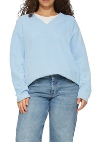 Lichtblauwe sweatshirt met een V-halsontwerp, geribde afwerking en lange mouwen, gecombineerd met lichte denim jeans. Zachte, gestructureerde stof.