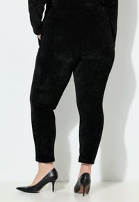 Zwarte corduroy leggings met een aansluitend ontwerp, met een gladde textuur en een hoge tailleband. Gecombineerd met puntige zwarte hoge hakken.