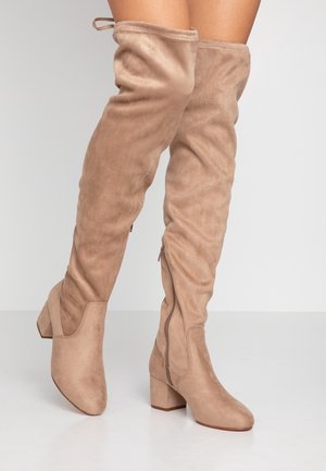 Botas de ante beige hasta la rodilla, con punta redonda y tacón cuadrado, que cuentan con una cremallera lateral y textura fruncida en la parte superior.