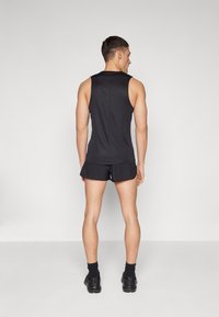 Black sleeveless tank top and shorts, made of smooth fabric, with a fitted design. The outfit features a streamlined cut and minimalist style.