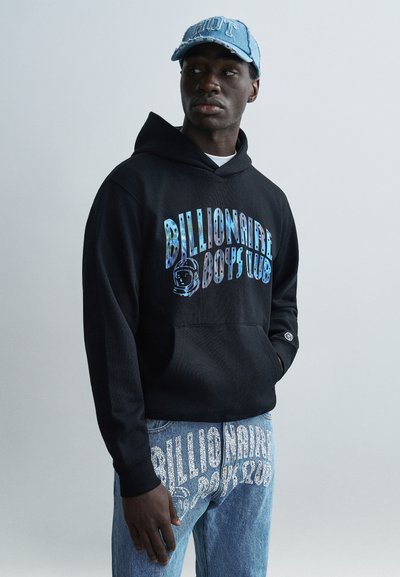 Black hoodie with multicolored "Billionaire Boys Club" graphic, paired with light blue distressed denim. Comfortable fit, front pocket detail.