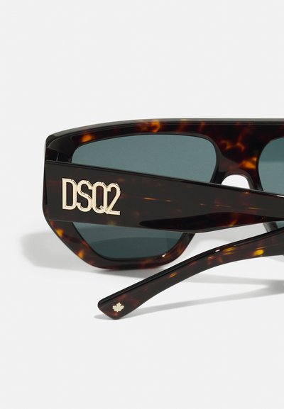 Óculos de sol em tartaruga com lentes verdes escuras, apresentando um logo dorado "DS02" na armação e um destaque em forma de folha de bordo dourada na haste.