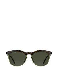 Occhiali da sole in tartaruga marrone con dettagli in verde, caratterizzati da montature quadrate arrotondate e lenti scure. Logo Lacoste sulla lente sinistra.