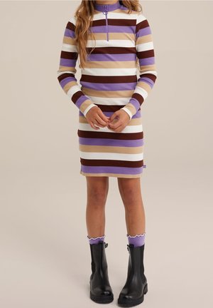 Barn iført en langærmet, knælængde kjole med vandrette striber i lilla, brun, beige og hvid, kombineret med lilla sokker og sorte støvler.