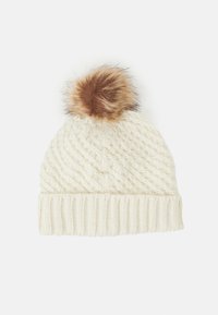 Cable-knit cream beanie with a ribbed cuff and a brown faux fur pom-pom on top. The texture is soft and warm, suitable for winter wear.