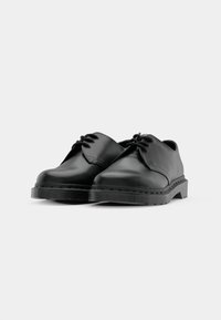 Black leather lace-up shoes with a smooth finish, rounded toe, and textured rubber sole. Minimalist design without additional accents.