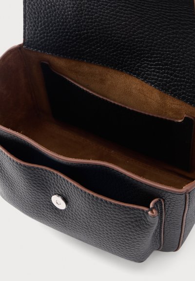 Μαύρη τσάντα χειρός από υφή δέρματος, ανοιχτή για να δείξει το καφέ εσωτερικό από σουέτ και ασημένια μαγνητική κούμπωμα στην εμπρόσθια πτυχή.