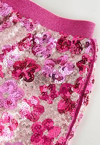 Pinker Paillettenstoff mit floralen Mustern, einem glitzernden pinken Bund und einer strukturierten, reflektierenden Oberfläche.