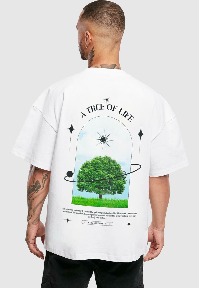 Bílý oversized tričko s grafikou zeleného stromu v rámovaném designu, textem "STROM ŽIVOTA" a hvězdnými akcenty.