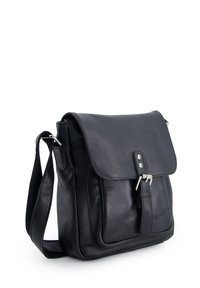 Czarna skórzana torba na ramię z przednią klapą, zapięciem na klamrę i regulowanym paskiem, stojąca na białym tle.