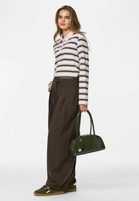 Roosade ja valgete triipudega pikkade varrukatega särk, millel on rohelised triibud, kombineeritud laia pruuni püksipaariga ning tumerohelise ümmarguse käekotiga.