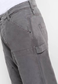 Grijze katoenen broek met een gladde textuur, voorzien van schuine zijzakken en een opgestikte zak. Gestikte details langs de naden.