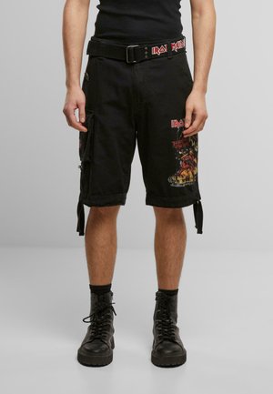 Black cargo shorts with graphic prints and logos, featuring multiple pockets, a belt, and adjustable side straps. Paired with black combat boots.