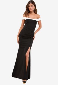 Črna obleka za večer z off-shoulder izrezom in belim obrežjem, prilega se telesu, z bočno režo in sproščenim krilom. Teksturiran material in eleganten dizajn.